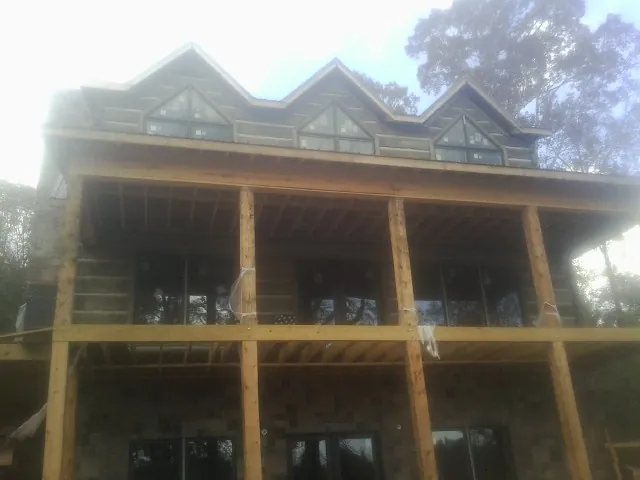 Dormers and porch framing on a large log home under construction — Roof Coating work by our crew in Bessemer