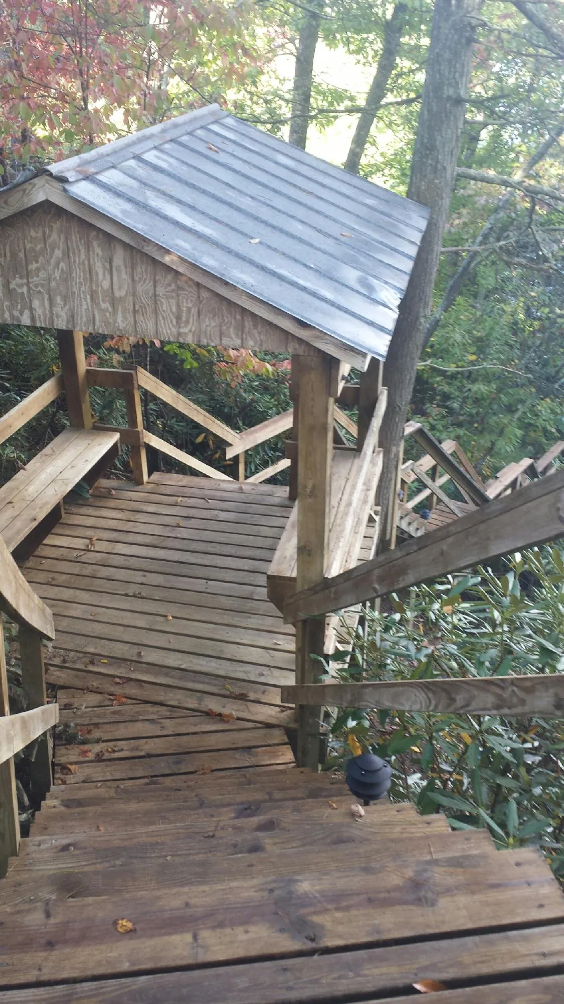 Metal roofed shelter over wooden steps on a wooded walkway — Skylight Repair & Installation work by our crew in Bessemer