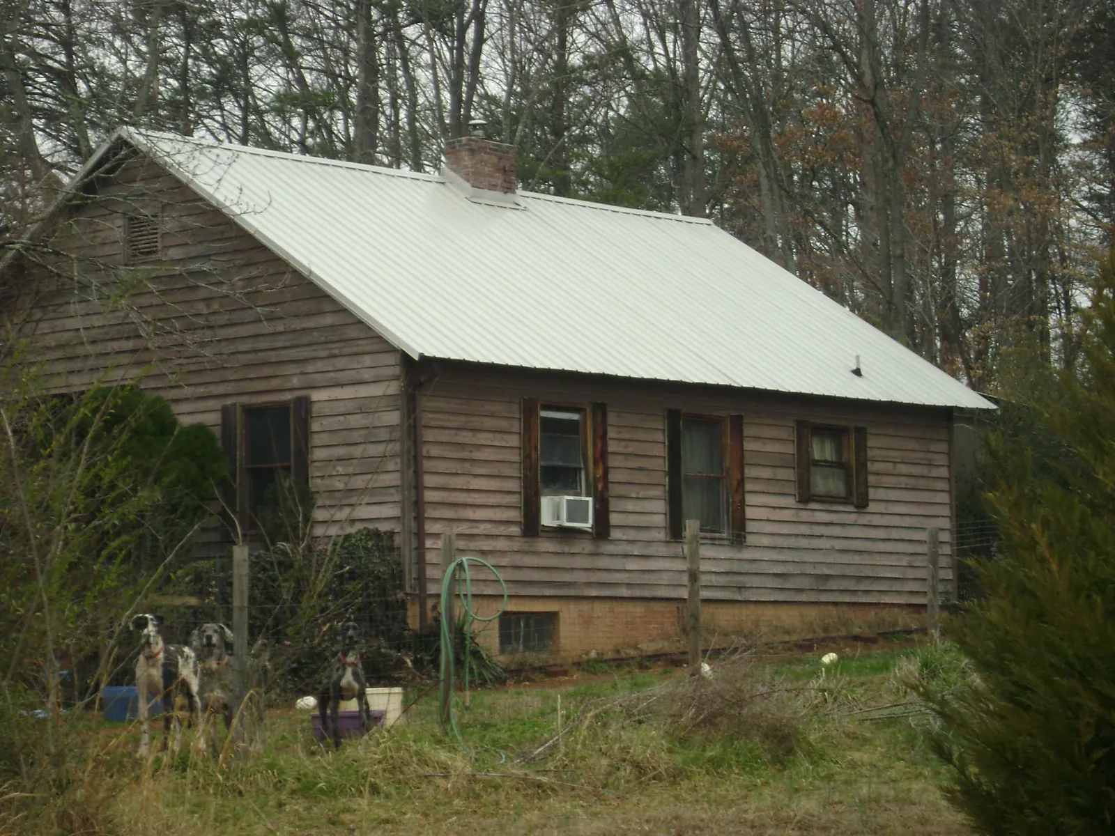 White metal roof on an old wood sided farmhouse, from a Metal Roof Installation job in Bessemer